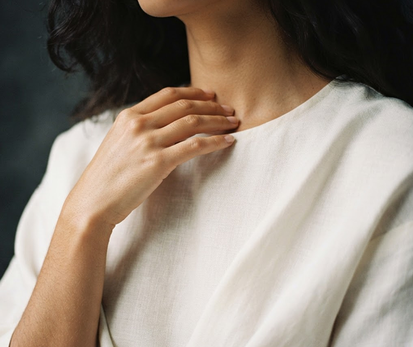 A hand resting at the collarbone where fragrance was applied